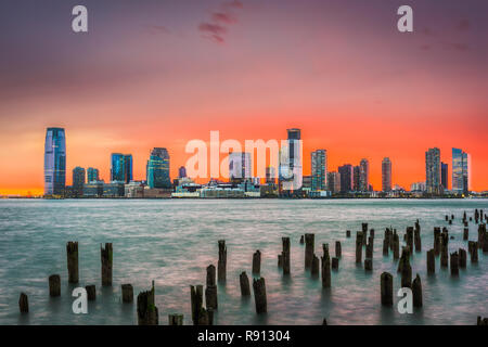 Jersey City, New Jersey, USA Skyline über den Hudson River nach Sonnenuntergang. Stockfoto