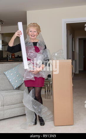 Frau Öffnen einer Box mit eine übermäßige Menge Schutzhülle aus Kunststoff Verpackungsmaterial Stockfoto