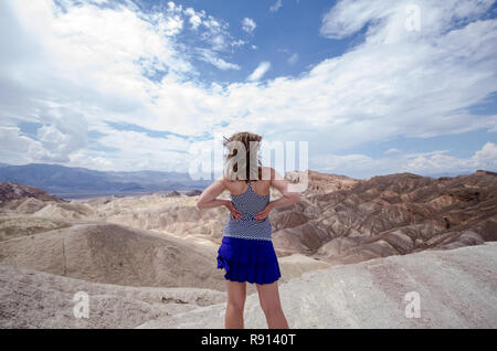 Erwachsene Frau mit nach hinten, um die Kamera auf Zabriskie Point im Death Valley National Park, Kalifornien. Haar weht im Wind an einem sonnigen Tag, trug Tank Stockfoto