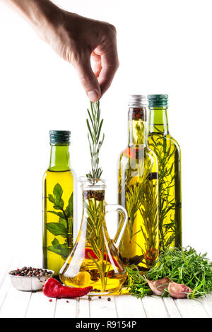 Man Rosmarin in die Flasche mit Ölen, Kräutern und Gewürzen auf weißem Hintergrund Stockfoto