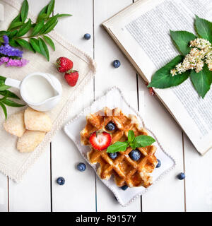 Wafer mit Beeren, Buch und Blumen auf der weißen Tisch Stockfoto