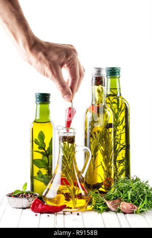 Mann, roter Chili in der Flasche mit Ölen, Kräutern und Gewürzen auf weißem Hintergrund Stockfoto