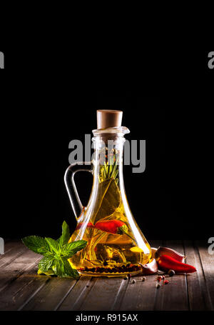 Mit Ölen, Kräutern und Gewürzen auf schwarzem Hintergrund Flasche Stockfoto