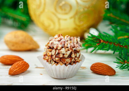 Hausgemachte Schokolade Trüffel mit Mandeln auf weiße Holztisch mit Tannenzweigen und festlichen Spielzeug Bälle. Geschenk für Weihnachten und das neue Jahr. Gourmet. Sel Stockfoto