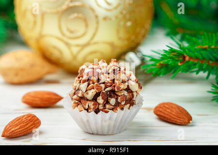 Hausgemachte Schokolade Trüffel mit Mandeln auf weiße Holztisch mit Tannenzweigen und festlichen Spielzeug Bälle. Geschenk für Weihnachten und das neue Jahr. Gourmet. Sel Stockfoto