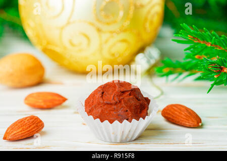 Hausgemachte Schokolade Trüffel mit Mandeln und Kakao auf weissem Holztisch mit Tannenzweigen und festlichen Spielzeug Bälle. Geschenk für Weihnachten und das neue Jahr. Gehen Stockfoto