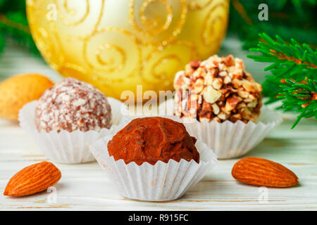 Hausgemachte Schokolade Trüffel mit Mandeln, Kokos und Kekse crumb in einem weißen Teller auf dem Tisch mit Tannenzweigen und festlichen Spielzeug Bälle. Geschenk für Stockfoto