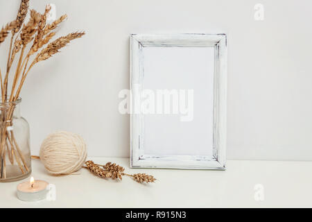 Vertikale Rahmen mockup mit wilden Roggen Blumenstrauß in glass vase in der Nähe von weißen Wand. Leeren Rahmen mock up für Presentation Design. Vorlage framing für moderne Ar Stockfoto