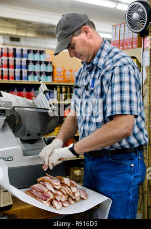 Sid Williams, einer der Inhaber von Williams Brothers General Store, Schichten Scheiben Speck, als er ein Paket in Philadelphia, Mississippi bereitet. Stockfoto