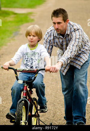 Ein autistischer Junge bekommt Hilfe von seinem Vater, wie er reitet sein Fahrrad auf einem steilen Hügel, April 21, 2012, in New Hope, Mississippi. Stockfoto
