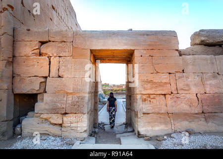 Eine junge Frau zu Fuß durch einen großen Stein Tür in einem ägyptischen Tempel Stockfoto
