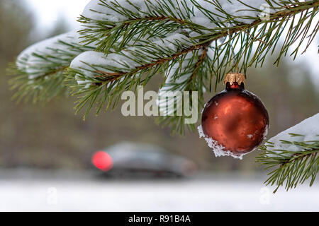 Red christmas Ball auf den verschneiten Tannen Filiale neben der Autobahn. Stockfoto