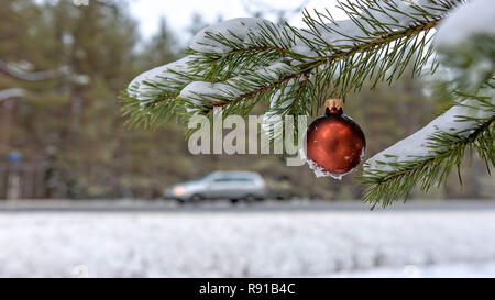 Red christmas Ball auf den verschneiten Tannen Filiale neben der Autobahn. Stockfoto