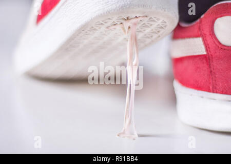 Sneakers Stepping in Kaugummi auf weiße Oberfläche. Klebrigen Kaugummi auf der Sohle der Sportschuhe. Klebrigkeit Konzept Stockfoto