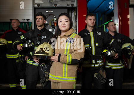 Foto von vier jungen männlichen und weiblichen Feuerwehrmänner auf dem Hintergrund der fire truck Stockfoto