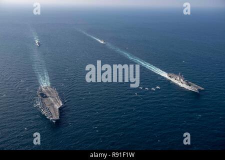 Ein U.S. Navy F/A-18 Super Hornet und Marine Corps B F-35 Lightning II Kampfflugzeug fliegen in Formation, wie der Flugzeugträger USS John C Stennis, Links, und die amphibischen Angriff Schiff USS Essex führen die geführte-missile Cruiser USS Mobile Bay und die Geführten-missile Cruiser USS Decatur im Gange, die sich in der Ausbildung zum 14. Dezember 2018 in das Arabische Meer. Stockfoto