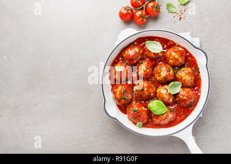Hausgemachte Frikadellen mit Tomaten und Gewürzen serviert pan in Weiß auf grauem Hintergrund. Ansicht von oben mit der Kopie. Stockfoto