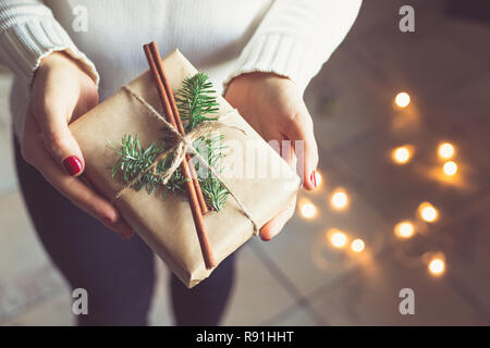 Mädchen im Winter weißen warmen Pullover hält einen geschmückten Geschenkkarton. Stockfoto