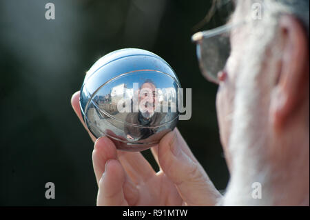 14.04.2010, Marne, Schleswig-Holstein, Deutschland - Siegfried Bersch, Leiter des Kultur- und Buergerhauses Marne, blickt in eine Boule-Kugel. 0 RX 100414 D1 Stockfoto