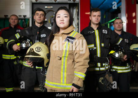 Portrait von vier jungen männlichen und weiblichen Feuerwehrmänner auf dem Hintergrund der fire truck Stockfoto