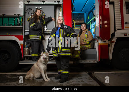 Foto von drei Frauen Feuerwehrmänner und Hund auf dem Hintergrund der fire truck Stockfoto