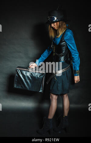 Reise und reisen. Retro elegante Unterkunft Mädchen mit Vintage big bag Koffer valise. Elegante viktorianische Frau auf dunklem Hintergrund. Stockfoto