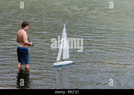Wörthersee, Österreich, - August 5, 2018: ein Mann aus der Ferne steuert eine Segelyacht Modell in einen kleinen See. Stockfoto