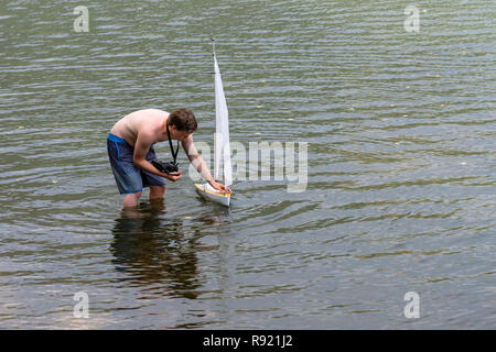 Wörthersee, Österreich, - August 5, 2018: ein Mann aus der Ferne steuert eine Segelyacht Modell in einen kleinen See. Stockfoto