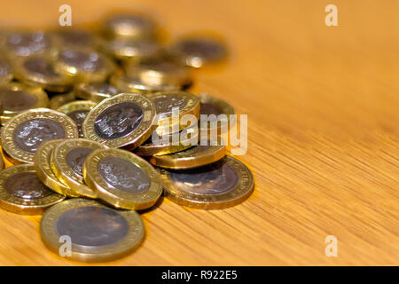 Stapel und Haufen von Britischen GBP goldenen Münzen Währung Geld auf Holz- Hintergrund mit leeren Raum Stockfoto
