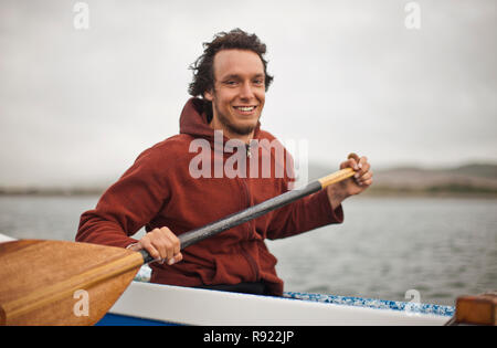 Porträt eines lächelnden jungen Mann Paddeln in einem Kanu. Stockfoto