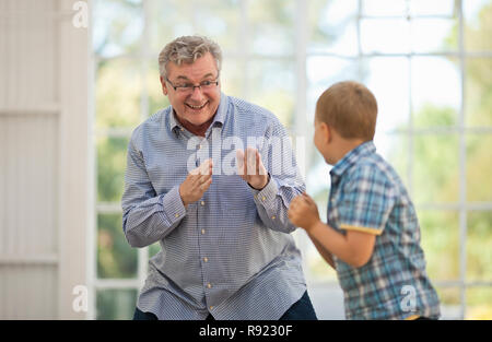 Lachend reifer Mann in einem Spiel Kampf mit seinem Enkel. Stockfoto