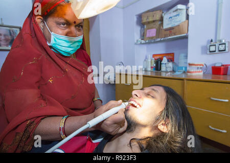 Weibliche barfuß Zahnarzt in traditioneller Kleidung und Mundschutz Behandlung der männlichen Patienten, Tilonia, Rajasthan, Indien Stockfoto