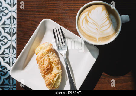 Blick von oben auf eine Latte mit blume Kunst und eine kubanische Cheese Roll Gebäck Stockfoto