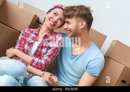 Junges Paar, der neue Ort Sitzung umarmt Hände halten Lachen heiter Stockfoto