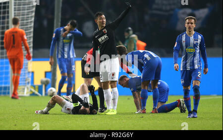 18. Dezember 2018, Berlin: Fußball: Bundesliga, Hertha BSC - FC Augsburg im Olympiastadion Berlin, Spieltag 16: Daniel Baier von Augsburg liegt auf dem Rücken auf dem Boden und Maximilian Mittelstädt von Hertha BSC kniet auf das Gras nach einem Zusammenstoß der Köpfe. Der Augsburger Dong-won Ji Wellen zu den Sanitätern. Foto: Andreas Gora/dpa - WICHTIGER HINWEIS: In Übereinstimmung mit den Anforderungen der DFL Deutsche Fußball Liga oder der DFB Deutscher Fußball-Bund ist es untersagt, zu verwenden oder verwendet Fotos im Stadion und/oder das Spiel in Form von Bildern und/oder Videos - wie Foto Sequenzen getroffen haben Stockfoto