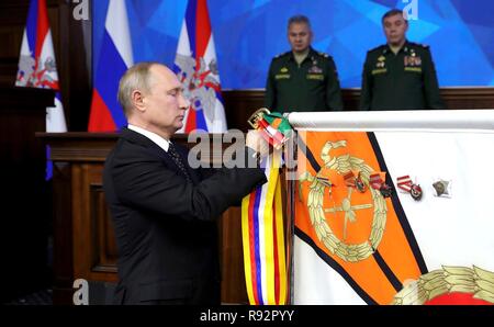 Moskau, Russland. 18. Dezember, 2018. Der russische Präsident Wladimir Putin den Stiften a regimental Flag während einer Zeremonie vor dem Treffen mit der militärischen Führung auf dem russischen Verteidigungsministerium Hauptsitz Dezember 18, 2018 in Moskau, Russland. Credit: Planetpix/Alamy leben Nachrichten Stockfoto