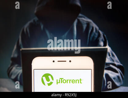 Hong Kong. 22 Nov, 2018. Utorrent Logo ist auf ein Android mobile Gerät mit einer Abbildung der Hacker im Hintergrund zu sehen. Credit: Miguel Candela/SOPA Images/ZUMA Draht/Alamy leben Nachrichten Stockfoto