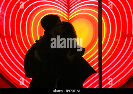 Die Oxford Street, London, 19. Dezember 2018. Ein paar Vor ein Herz Neon Licht Anzeige an John Lewis umfassen. Festliche Lichter und und bunten Fenster zeigt gehetzt Käufer in Kaufhäusern und Geschäften locken in der Oxford Street in London. Credit: Imageplotter Nachrichten und Sport/Alamy leben Nachrichten Stockfoto