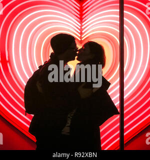 Die Oxford Street, London, 19. Dezember 2018. Ein paar Vor ein Herz Neon Licht Anzeige an John Lewis umfassen. Festliche Lichter und und bunten Fenster zeigt gehetzt Käufer in Kaufhäusern und Geschäften locken in der Oxford Street in London. Credit: Imageplotter Nachrichten und Sport/Alamy leben Nachrichten Stockfoto