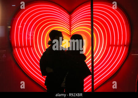 Die Oxford Street, London, 19. Dezember 2018. Ein paar Vor ein Herz Neon Licht Anzeige an John Lewis umfassen. Festliche Lichter und und bunten Fenster zeigt gehetzt Käufer in Kaufhäusern und Geschäften locken in der Oxford Street in London. Credit: Imageplotter Nachrichten und Sport/Alamy leben Nachrichten Stockfoto