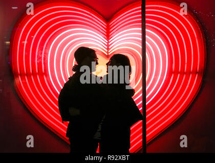 Die Oxford Street, London, 19. Dezember 2018. Ein paar Vor ein Herz Neon Licht Anzeige an John Lewis umfassen. Festliche Lichter und und bunten Fenster zeigt gehetzt Käufer in Kaufhäusern und Geschäften locken in der Oxford Street in London. Credit: Imageplotter Nachrichten und Sport/Alamy leben Nachrichten Stockfoto