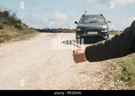 Nahaufnahme eines männlichen touristische Trampen. Er hob den Finger auf und versucht, das Auto seine Reise fortsetzen zu stoppen. Stockfoto