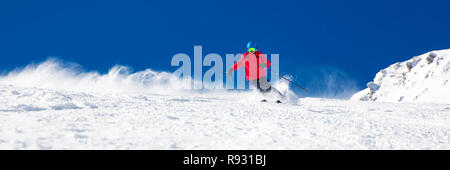 Man Skifahren auf der präparierten Piste mit neuen, frischen Pulverschnee. Stockfoto