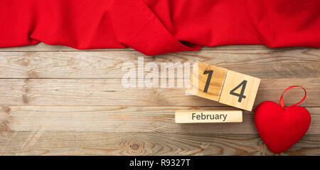 Valentines Tag. Blick von oben auf die roten Herzen und Kalender Holzwürfel mit 14. Februar text und roten Tuch gegen Holz- Hintergrund Stockfoto