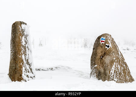 Wandern Pfeil Zeichen auf Stein in tiefem Schnee, Winter inspirierende Landschaft. Schönen inspirierenden Szene mit kopieren. Stockfoto