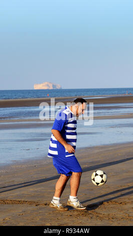 Ein OMANISCHES Mann spielt Fußball auf Qurum Beach in Maskat, Oman. Stockfoto