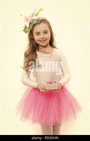 Mädchen ballerina Lächeln mit Blume im langen blonden Haare. Kind mit Box im rosa Tutu Rock isoliert auf Weiss. Urlaub, Geburtstag, Jubiläum zu feiern. Vorhanden oder Geschenk geben. Boxing Day Konzept. Stockfoto