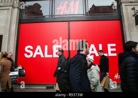 Shopper sind gesehen zu Fuß durch ein Schild an der Londoner Oxford Street mit 6 Tage bis Weihnachten. Händler rechnen mit einem Ansturm der Käufer in der Leitung - bis zu Weihnachten als Umsatz in H&M hat begonnen. Stockfoto