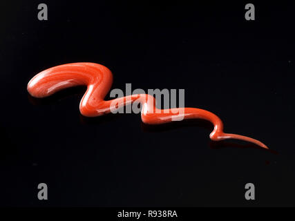 Textur aus rotem Lipgloss Flüssigkeit, schwarzer Hintergrund Stockfoto