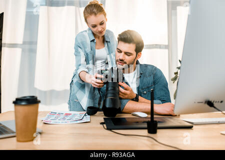 Professionelle lächelnden jungen Fotografen, die mit Foto Kamera zusammen im Büro Stockfoto